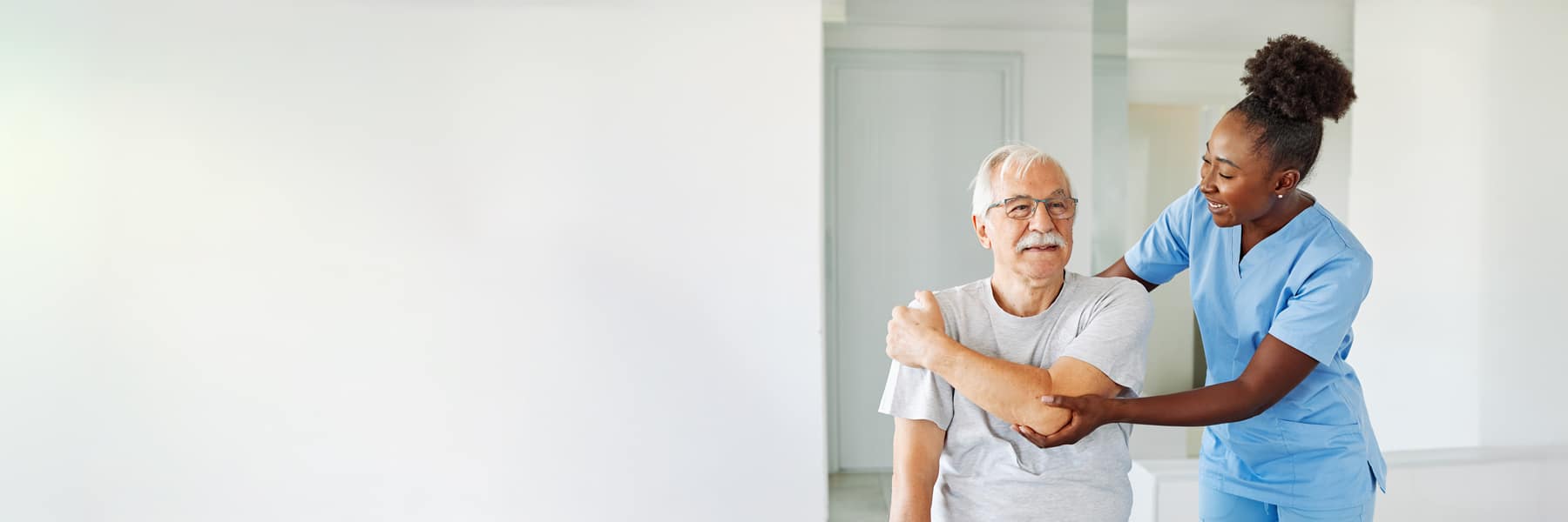 man doing arm stretches with the help of his care provider